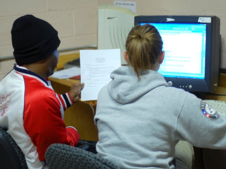An AmeriCorps volunteer helps a hurricane victim compose a resume in at the Community Center of St. Bernard in New Orleans.